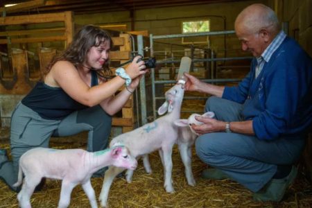 Amanda Meunier photographiant un paysan donnant le biberon à un agneau