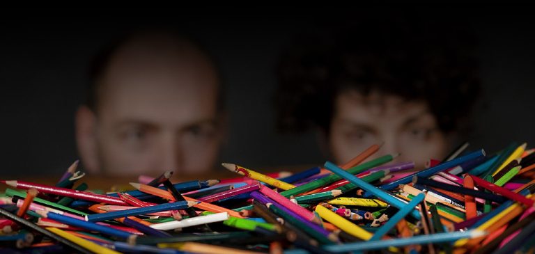 deux visages flous derrière des crayons de couleur