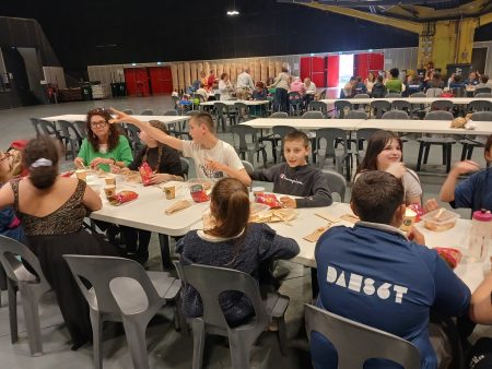 des jeunes assis à des tables en train de manger.