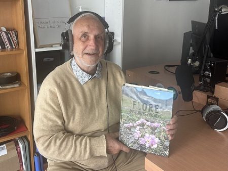 Portrait de l'auteur en pull-over beige avec son livre dans le studio radio et le casque sur les oreilles