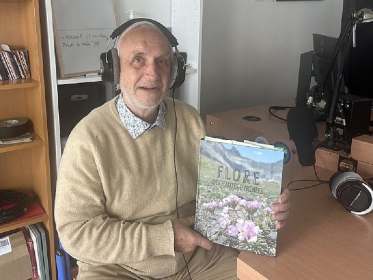 Portrait de l'auteur en pull-over beige avec son livre dans le studio radio et le casque sur les oreilles