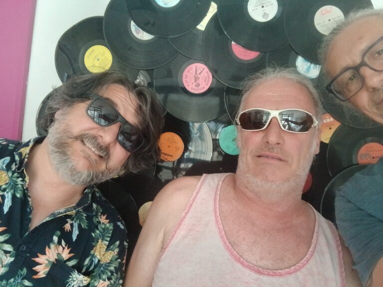 3 gars avec lunettes de soleil devant une sculpture de vinyls